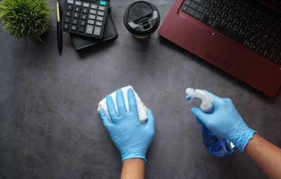 hand in blue rubber gloves holding spray bottle .